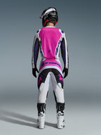 Alpinestars 2026 Fluid Grid trøje og matchende bukser, motocross-udstyrssæt, lyserød, hvid og lilla, set bagfra med ergonomisk atletisk pasform, båret med sort hjelm og hvide støvler, designet til off-road præstation