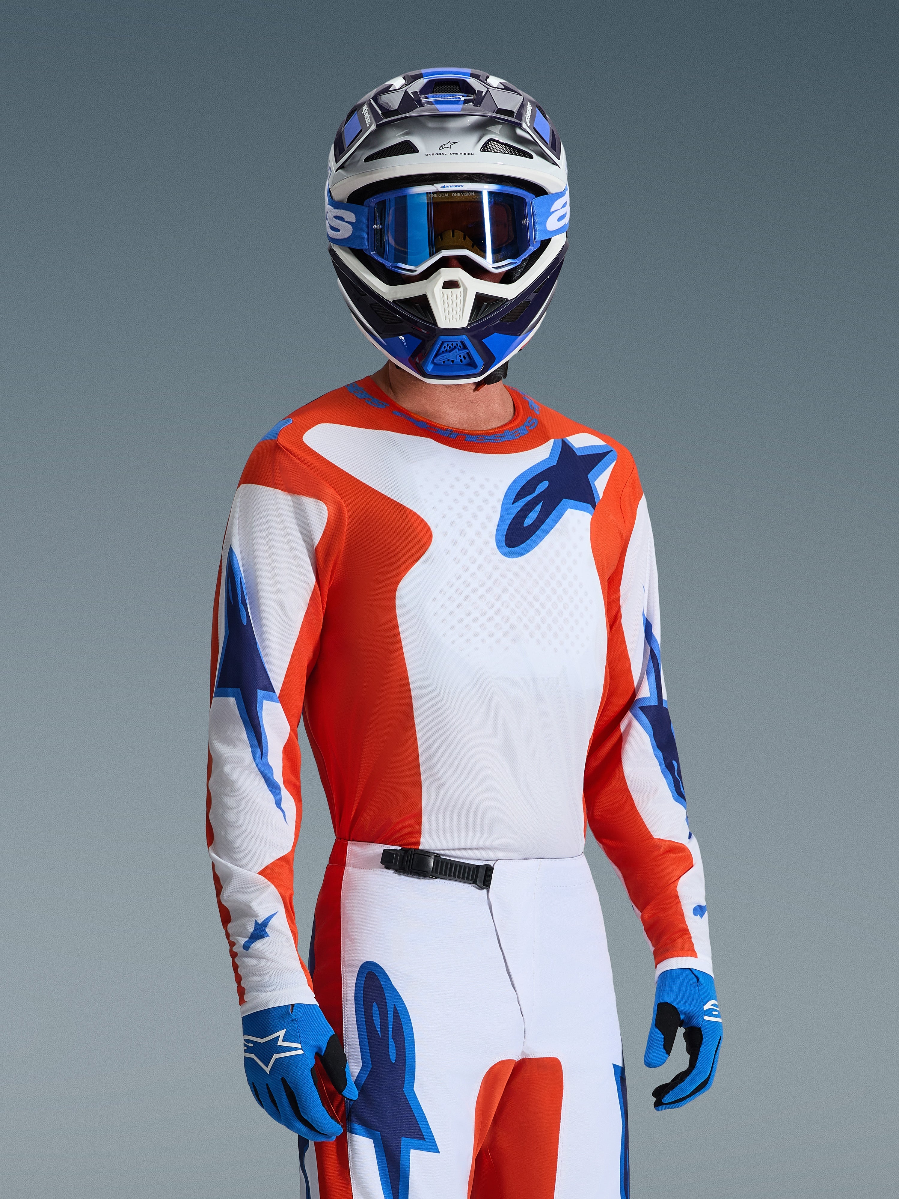 Alpinestars 2026 Fluid Grid trøje, motocrosstrøje i Orange UCLA Blue, båret af en kører med matchende hvide og orange bukser, blå og hvid hjelm, blå goggles og blå handsker, komplet off-road racerudstyrssæt