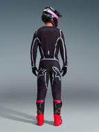 Motocross-kører set bagfra iført Alpinestars 2026 Fluid Apex trøje og matchende bukser i sort og grå, med hvide geometriske designlinjer og stjernelogoer på bagdelen, suppleret med en sort og pink hjelm og røde og sorte racingstøvler.