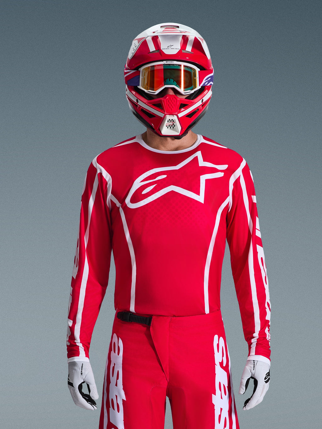 Alpinestars 2026 Fluid Apex trøje, motocross-trøje, rød og hvid, båret af en kører med en matchende rød og hvid hjelm og orange crossbriller, med et fremtrædende hvidt logo på brystet, atletisk pasform, en del af et koordineret off-road racing-sæt