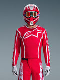 Alpinestars 2026 Fluid Apex trøje, motocross-trøje, rød og hvid, båret af en kører med en matchende rød og hvid hjelm og orange crossbriller, med et fremtrædende hvidt logo på brystet, atletisk pasform, en del af et koordineret off-road racing-sæt