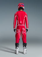Bagfra af en motocrosskører iført Alpinestars 2026 Fluid Apex-udstyrssæt, klar rød trøje og bukser med hvide striber og logoer, kombineret med hvide og sorte støvler og en rød hjelm, professionelt off-road racerudstyr