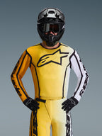 Motocro s s-køre r i ført Alpine st ar s 20 26 Flu i d Apex-u d s t yr s sæt, gul og hv i d jersey med st o r t s o r t st jer n e l o go, m at ch e n de gu le og h v i de b u k ser, s or t h jelm med s or te goggl e s og s or te h a n d sker, k o o rd i n er et ou tf i t til o f f-ro a d r a c i n g