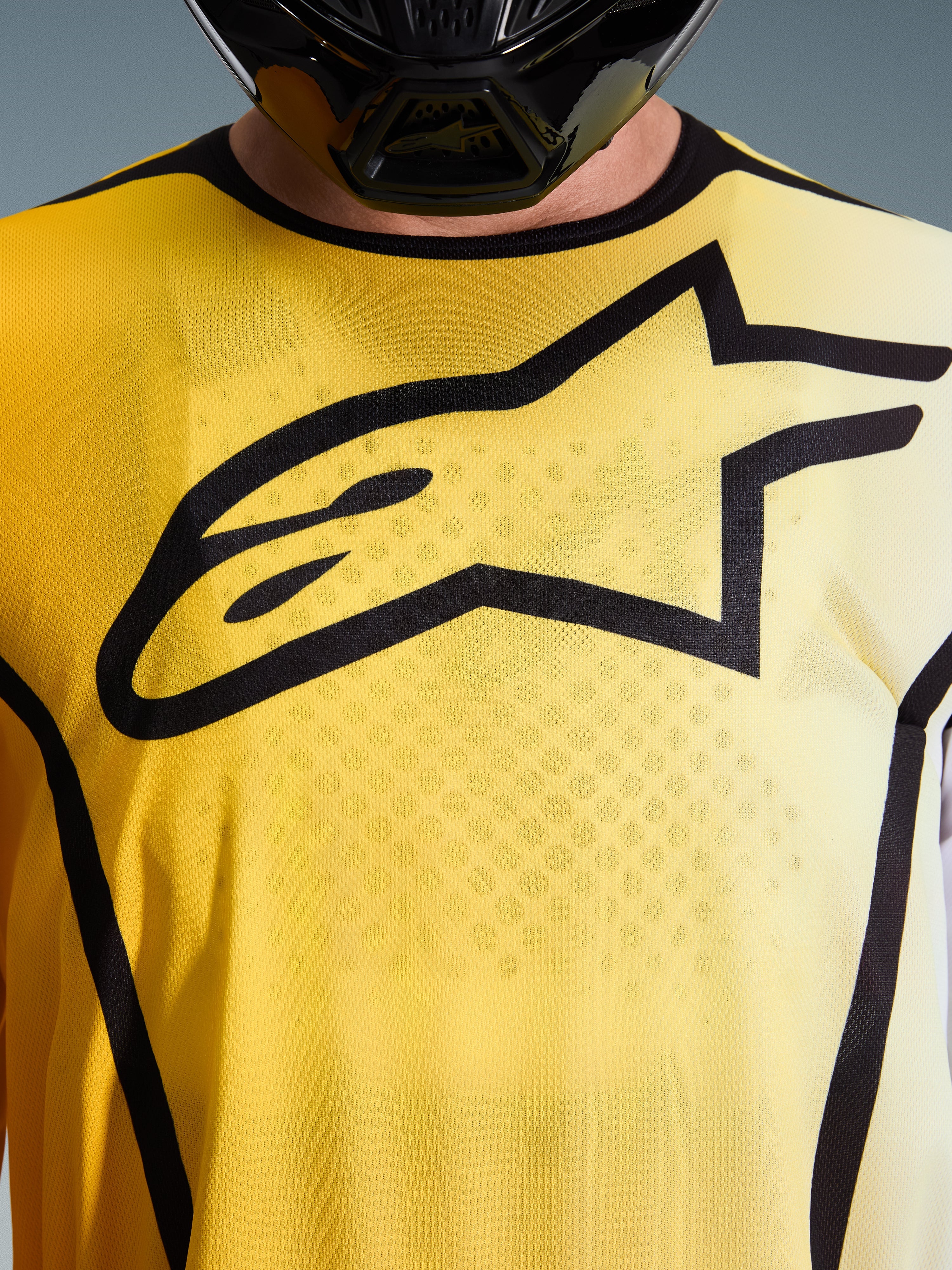 Alpinestars 2026 Fluid Apex jersey, motocrosstrøje, klar gul og sort, nærbillede med et stort sort Astar-logo på brystet, åndbart fugttransporterende poly-tekstil med sportskrave.