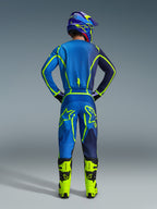 Motocross-kører set bagfra i fuldt racerudstyr, bestående af Alpinestars 2026 Fluid Apex-trøje og matchende bukser i Blue Yellow Fluo, med livlige neon-accenter og tydelig branding, kombineret med lyse gule støvler og en matchende hjelm.