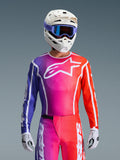 Motocross-kører iført 2026 Fluid Apex-trøjen, livligt lilla, pink og orange gradientdesign med et stort hvidt Alpinestars-logo på brystet, kombineret med en hvid hjelm, lilla goggles og hvide handsker for et komplet off-road racing-look.