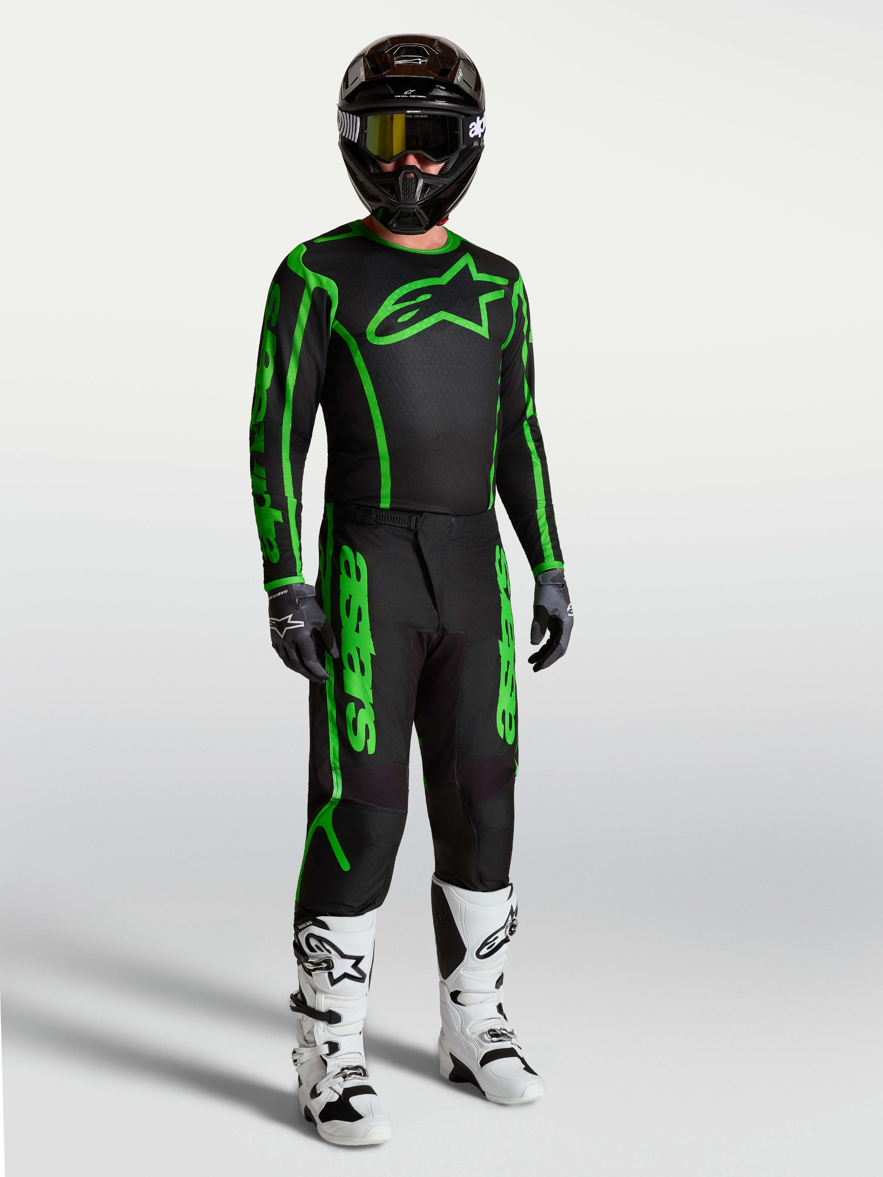 Alpinestars Fluid Apex V2 bukser, herre-motocrossudstyr, sort og fluorescerende grøn, vist med hvide støvler.
