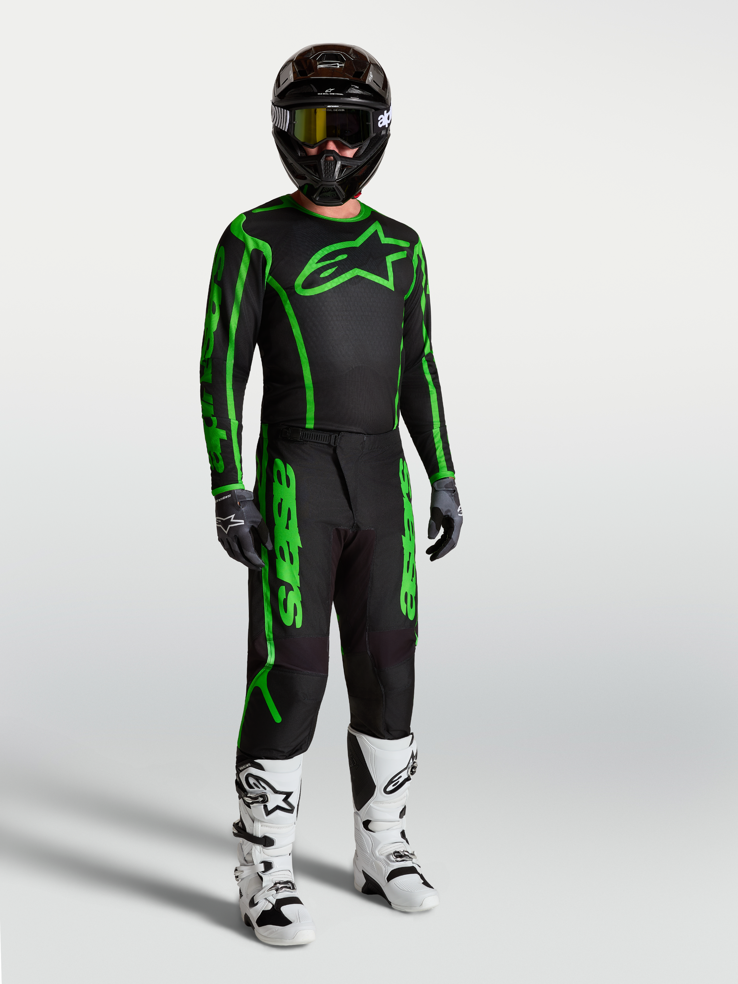 Alpinestars Fluid Apex V2 trøje, motocrosstrøje til herrer, sort og grøn, vist på model med matchende bukser og støvler.