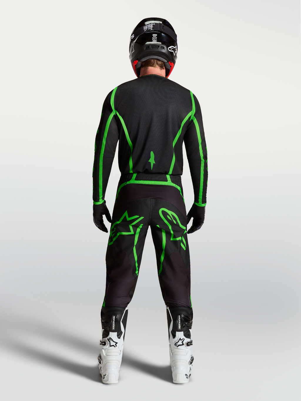 Alpinestars Fluid Apex V2 bukser, herre motocrossbukser, sort og grøn, set bagfra på en rytter med hvide motorcykelstøvler.