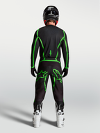 Alpinestars Fluid Apex V2 bukser, herre motocrossbukser, sort og grøn, set bagfra på en rytter med hvide motorcykelstøvler.