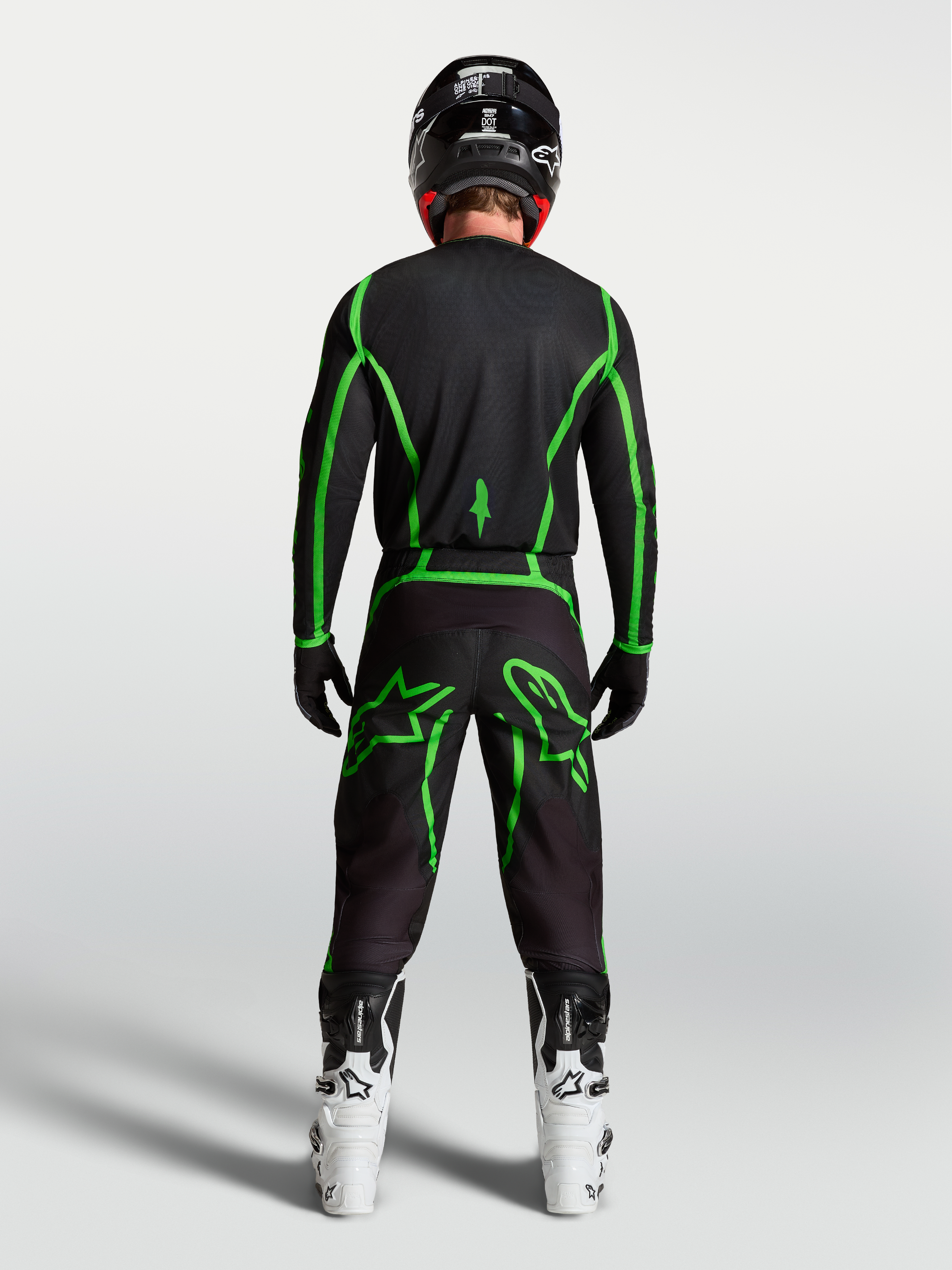 Alpinestars Fluid Apex V2 bukser, herre motocrossbukser, sort og grøn, set bagfra på en rytter med hvide motorcykelstøvler.