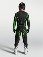 Alpinestars Fluid Apex V2 trøje, motocrosstrøje til herre, sort og fluorescerende grøn, set bagfra på kører med hvide støvler.