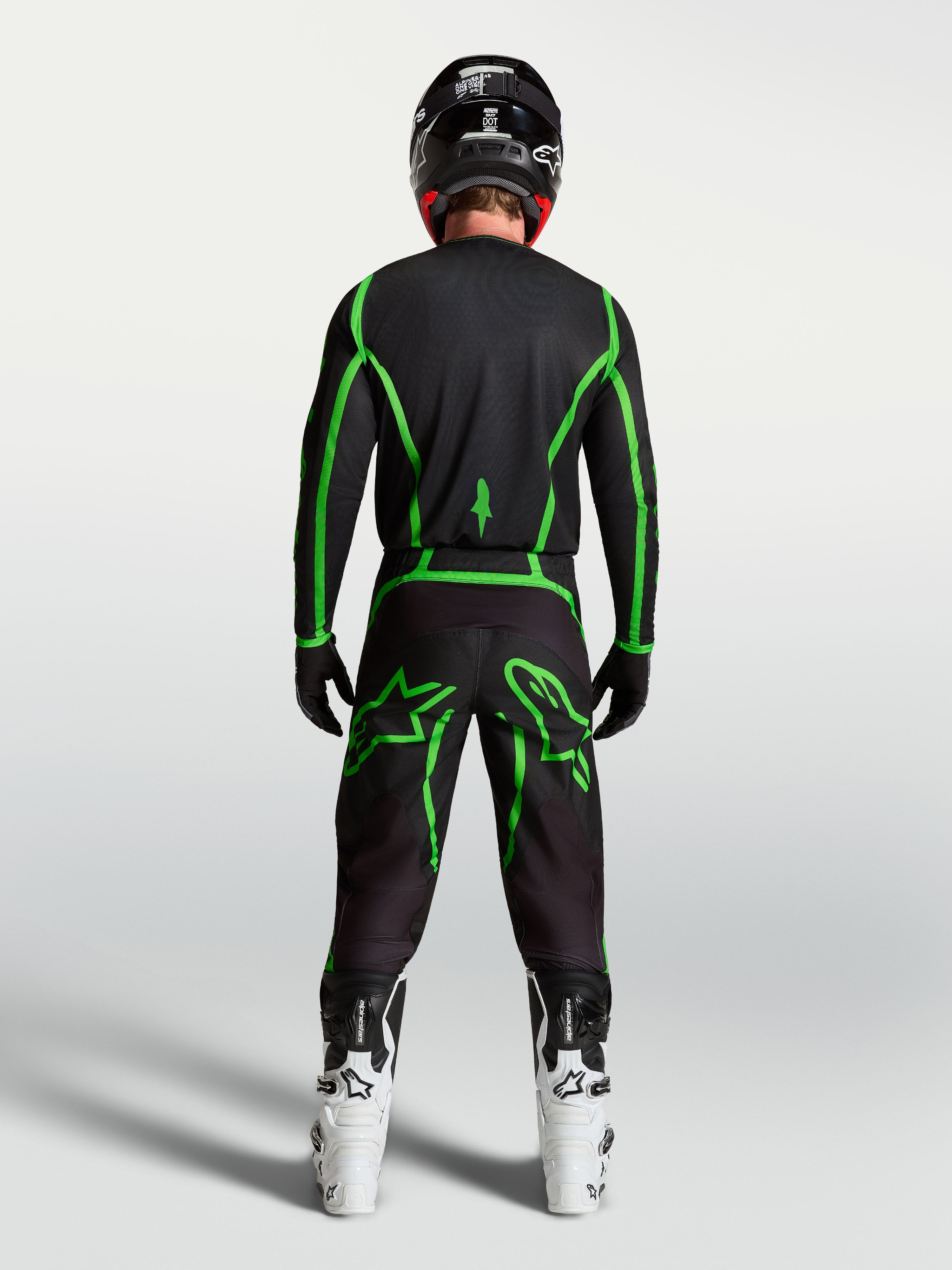 Alpinestars Fluid Apex V2 trøje, motocrosstrøje til herre, sort og fluorescerende grøn, set bagfra på kører med hvide støvler.