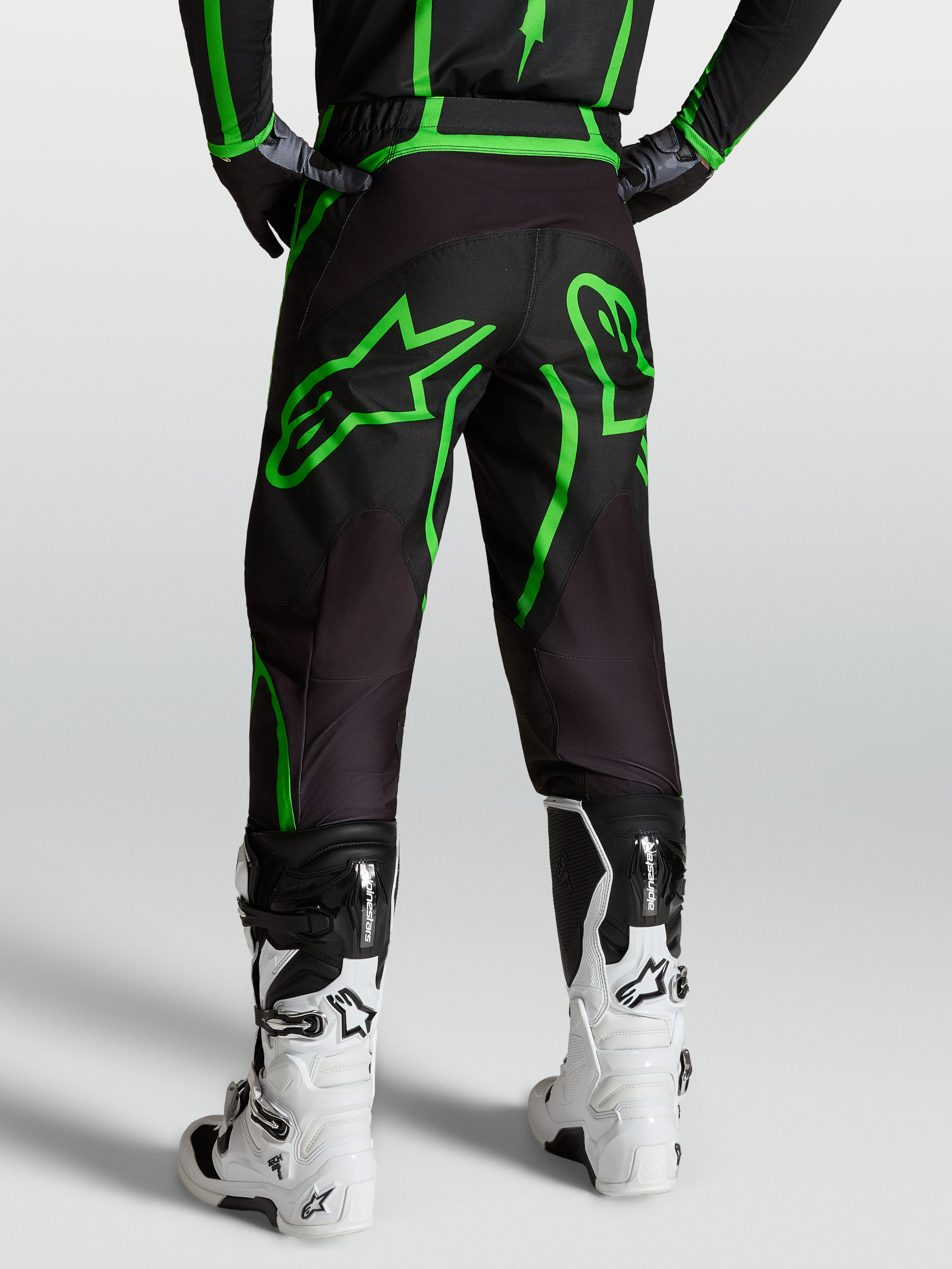 Alpinestars Fluid Apex V2 bukser, motocross- og off-road herrebukser, sort og grøn, set bagfra på model med hvide støvler