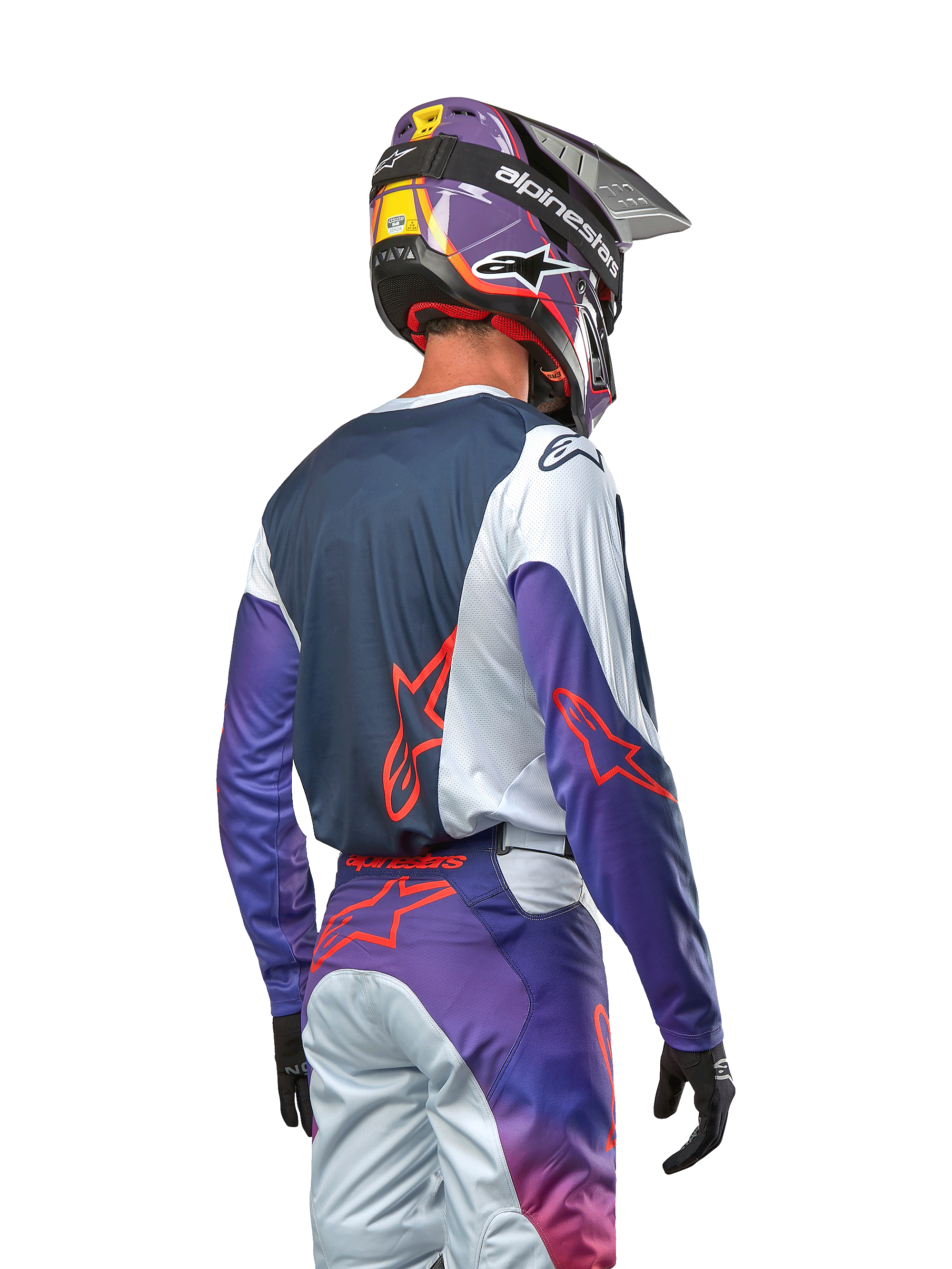 Motocrosskører set bagfra iført 2024 Racer Hoen Jersey, marineblåt rygpanel med lysegrå skuldre og lilla ærmer, stærkt orange Alpinestars-logoer, matchende lilla og grå bukser med en lilla motocrosshjelm, komplet off-road racersæt