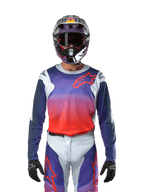 Alpinestars 2024 Racer Hoen trøje i Light Gray Hot Orange Black, motocross-trøje båret af en kører med matchende udstyr, med en vibrant farveovergang og Alpinestars stjernelogo på brystet, designet til off-road ydeevne.