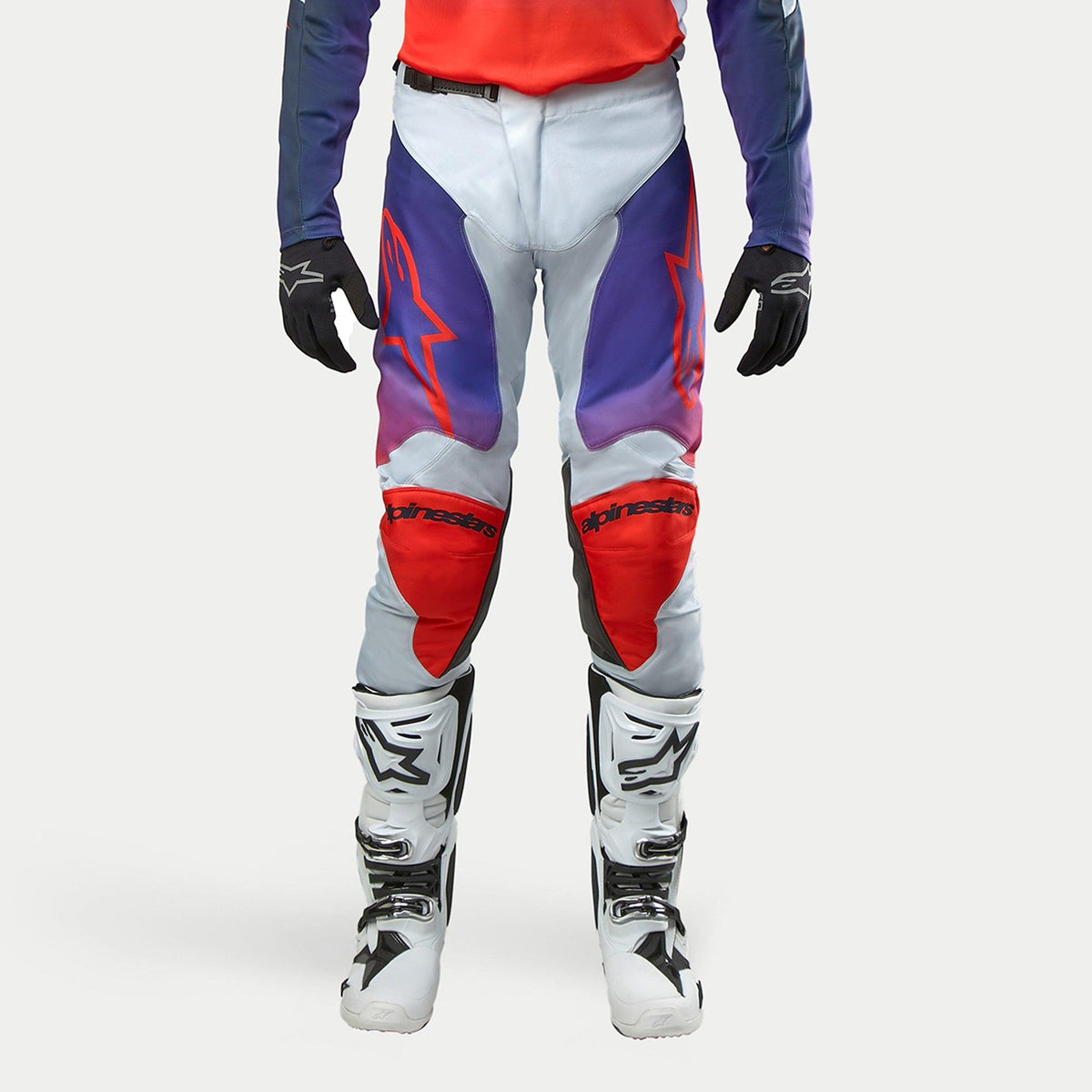 Alpinestars 2024 Racer Hoen bukser, motocross off-road bukser, lysegrå med hot orange og lilla gradientdetaljer, røde knæpaneler, frontvisning, herre, vist med hvide motorcykelstøvler og sorte handsker, beskyttelsesudstyr til terrænkørsel
