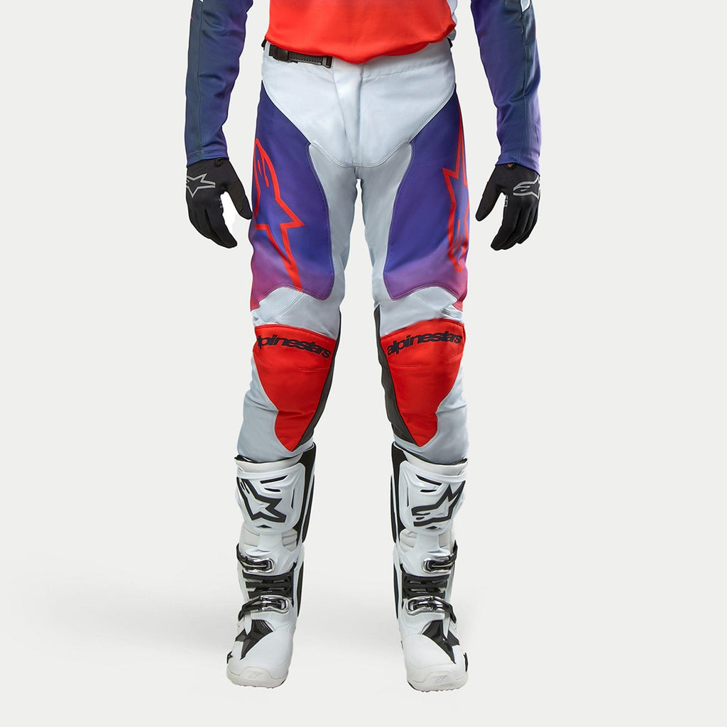 Alpinestars 2024 Racer Hoen bukser, motocross off-road bukser, lysegrå med hot orange og lilla gradientdetaljer, røde knæpaneler, frontvisning, herre, vist med hvide motorcykelstøvler og sorte handsker, beskyttelsesudstyr til terrænkørsel