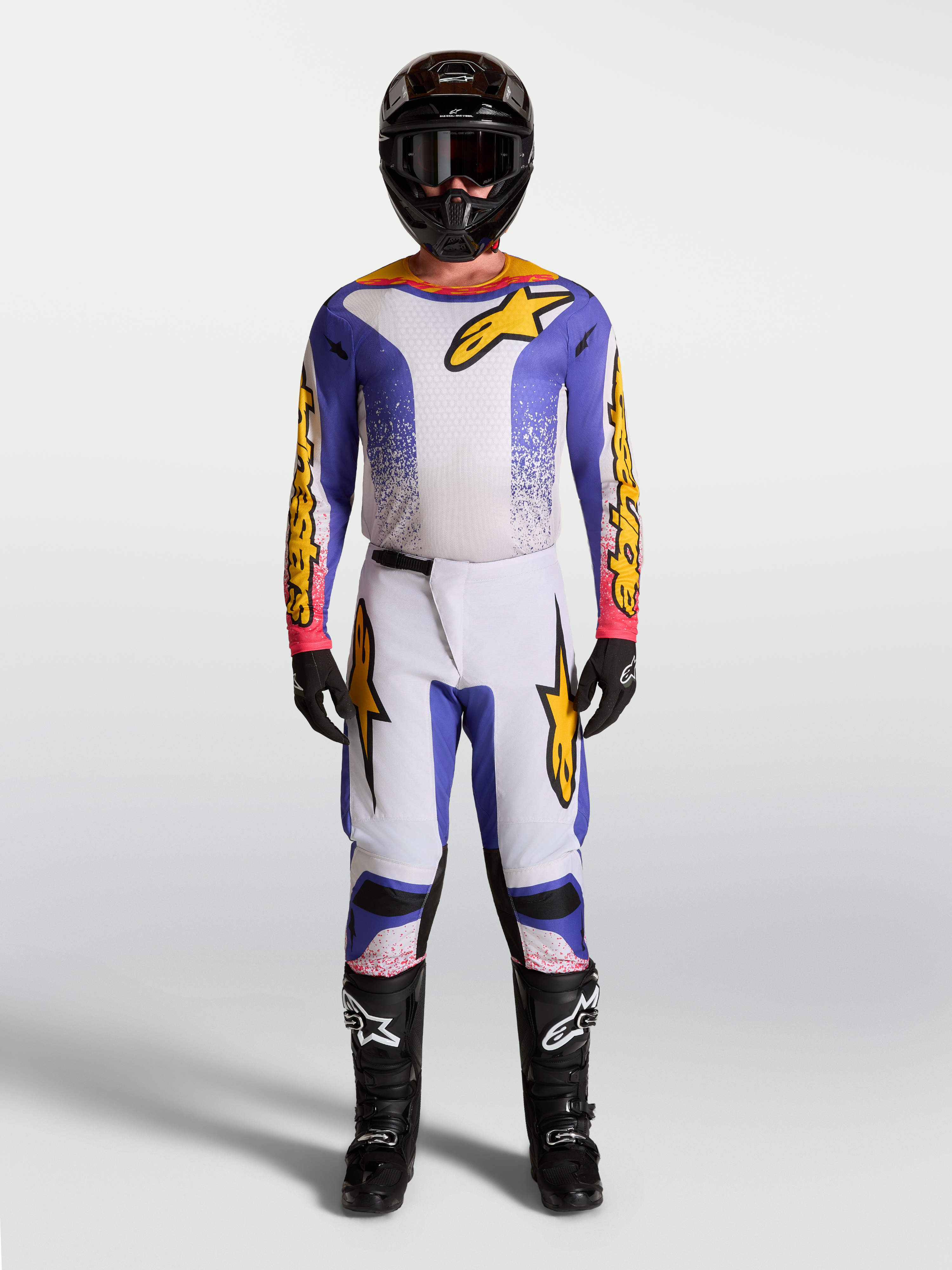 Alpinestars Fluid Drag motocross gear set in lilac, blue, and gold, featuring a matching jersey and pants.