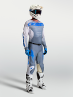 Alpinestars Racer Amber trøje, askegrå og blå motocrossgear til mænd, på model med hjelm og støvler.