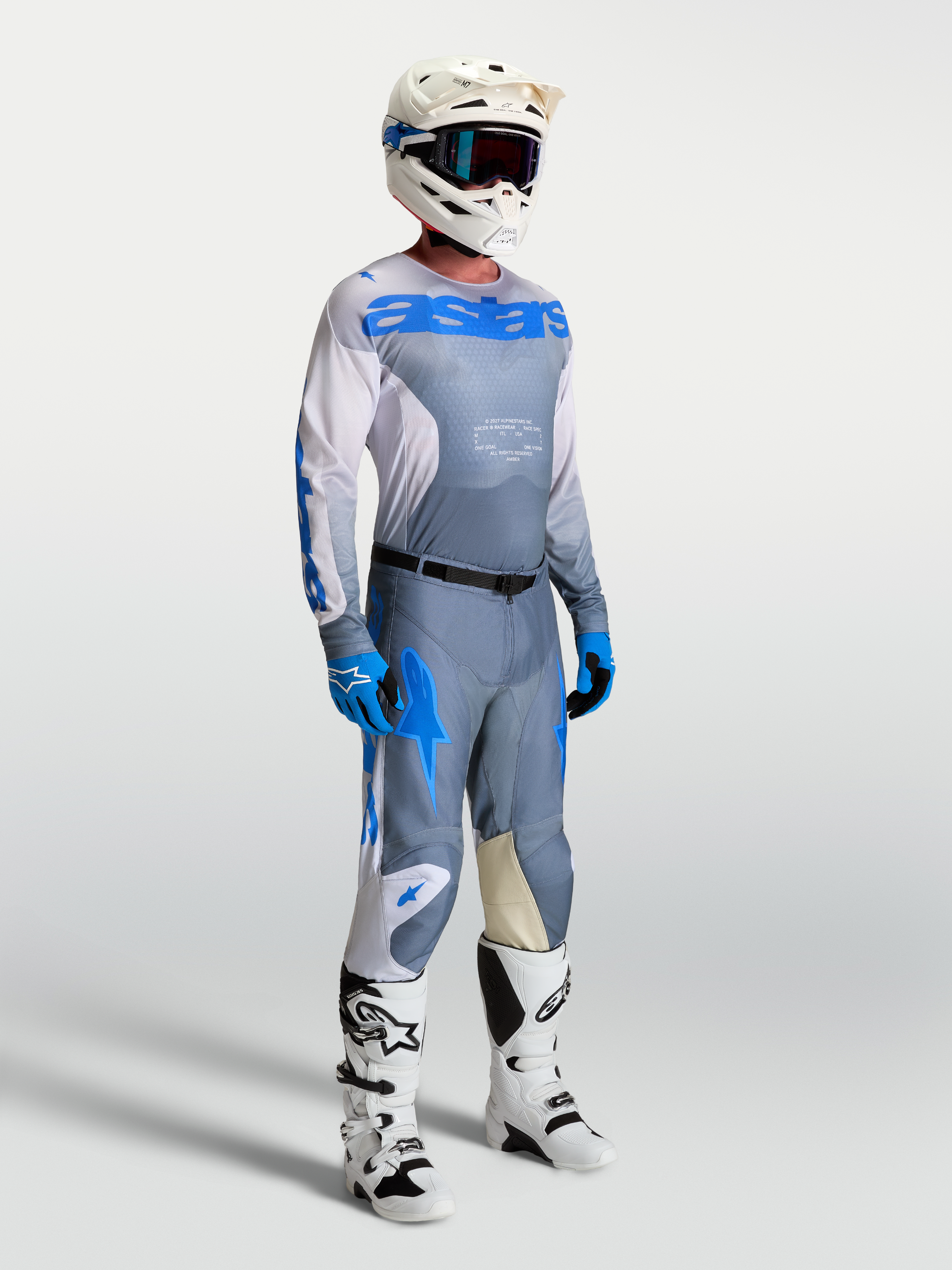 Alpinestars Racer Amber trøje, askegrå og blå motocrossgear til mænd, på model med hjelm og støvler.