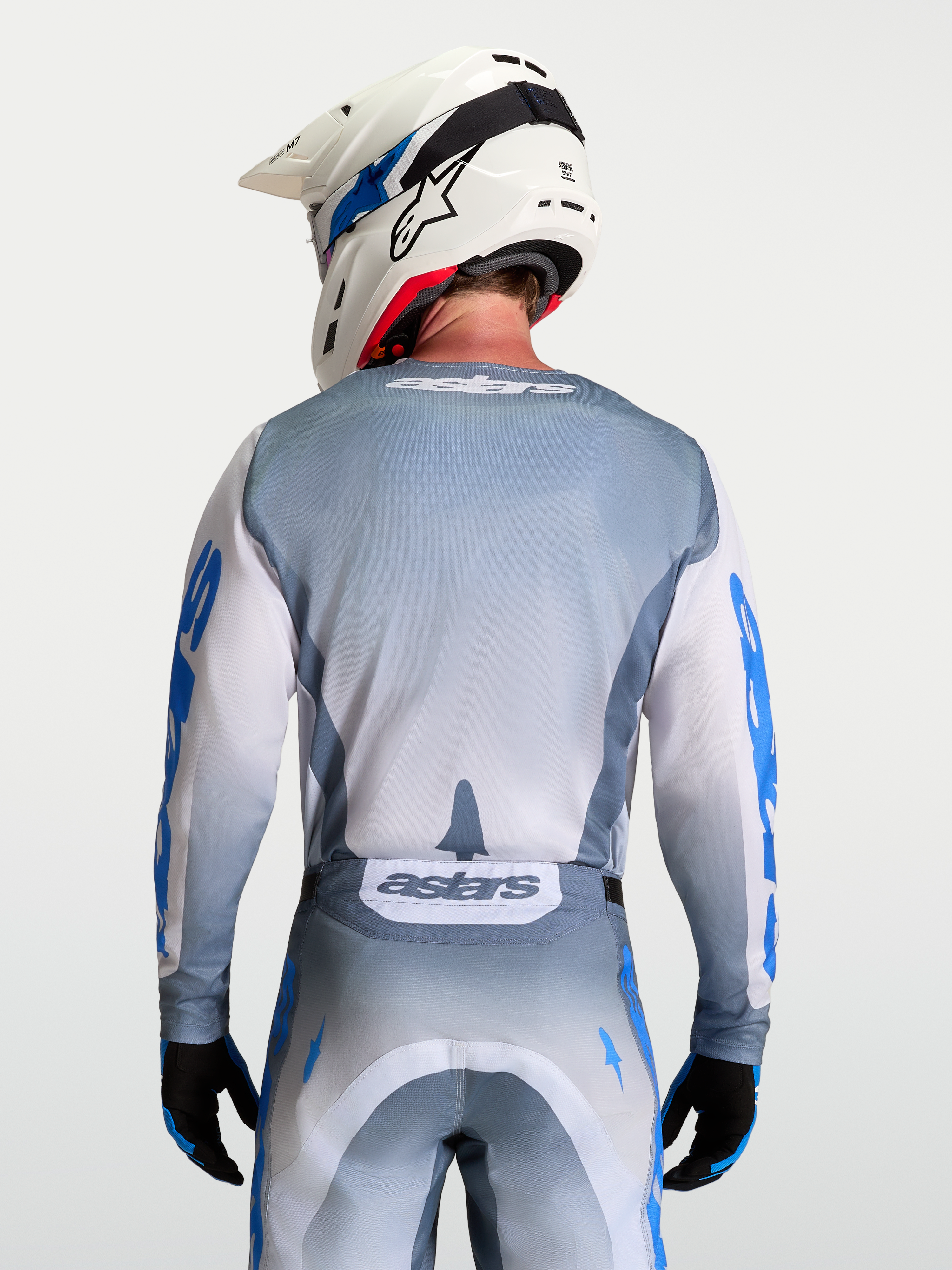 Alpinestars Racer Amber trøje, motocross trøje i grå og hvid, set bagfra på model med hvid hjelm, ergonomisk race pasform.
