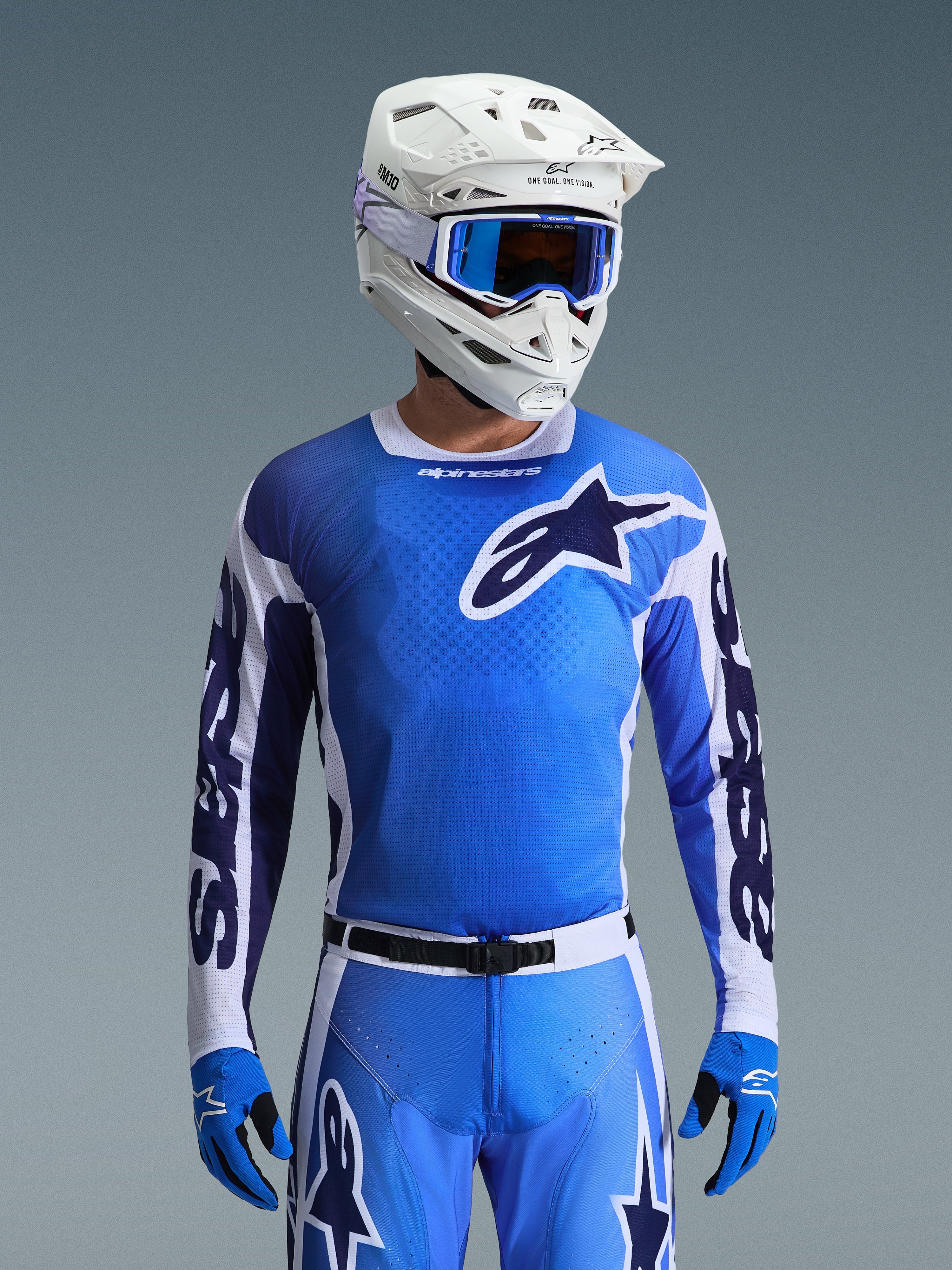 Alpinestars 2026 Racer Air Portl trøje i Ucla Blue og hvid, motocross-trøje med en åndbar mesh-konstruktion og markant stjernelogo, båret af en rytter med matchende bukser, hvid hjelm og blå briller for et koordineret off-road racersæt.