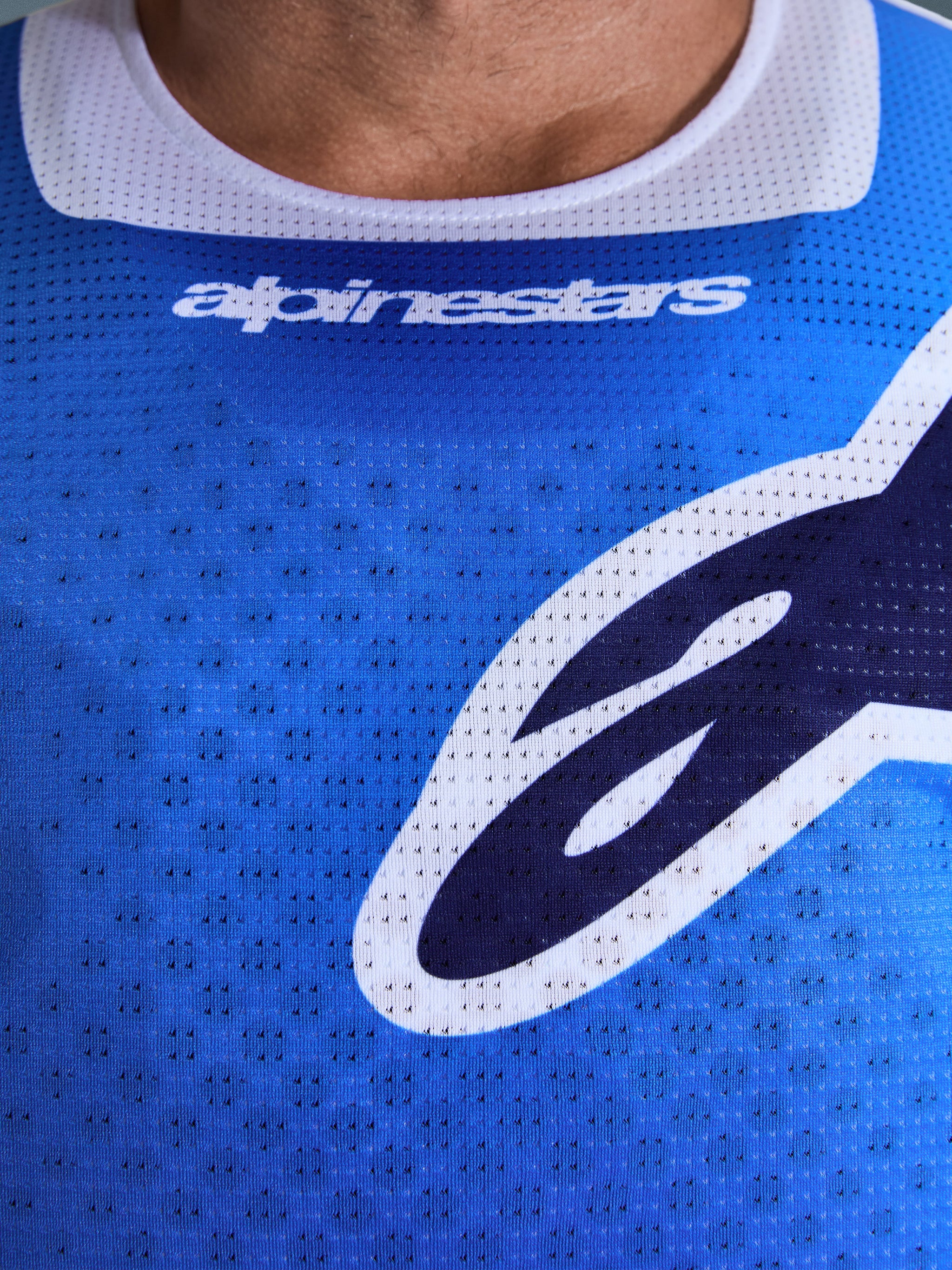 Alpinestars 2026 Racer Air Portl trøje, motocross-trøje, Ucla blå og hvid, nærbillede af brystet, der viser åndbart perforeret mesh-materiale, hvid kravekant og stiliserede Alpinestars-logoer