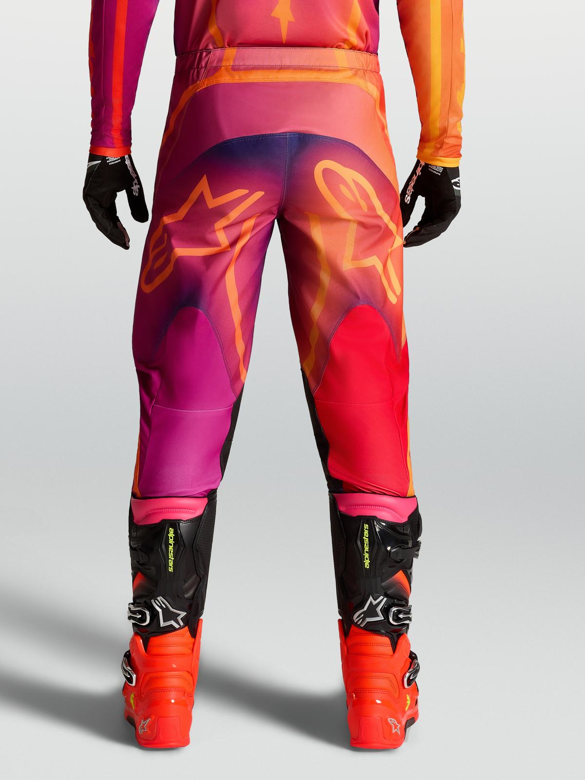 Alpinestars Fluid Kepler Pants, Men's Motocross Pants in Purple and Orange with rear star graphics and black racing boots.