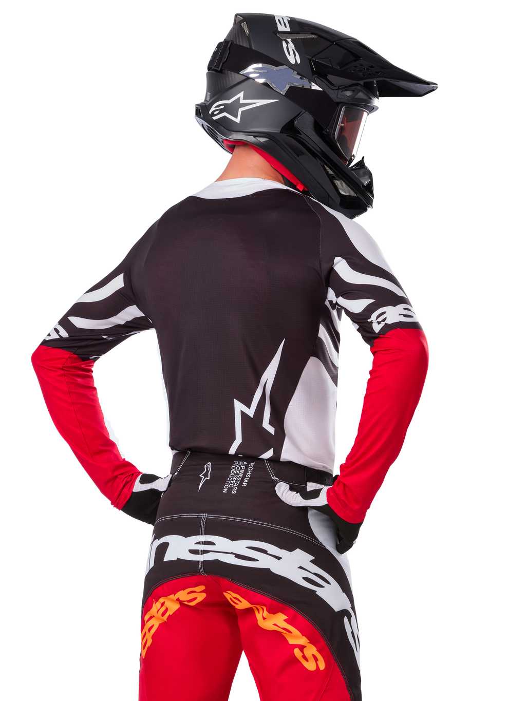 Motocrossrytter iført komplet racerudstyr, Alpinestars Limited Edition Techstar Deep jersey i sort, hvid og High Red, set bagfra, matchende Techstar Deep bukser, sort hjelm med goggles, sort-hvide handsker, professionelt off-road raceroutfit