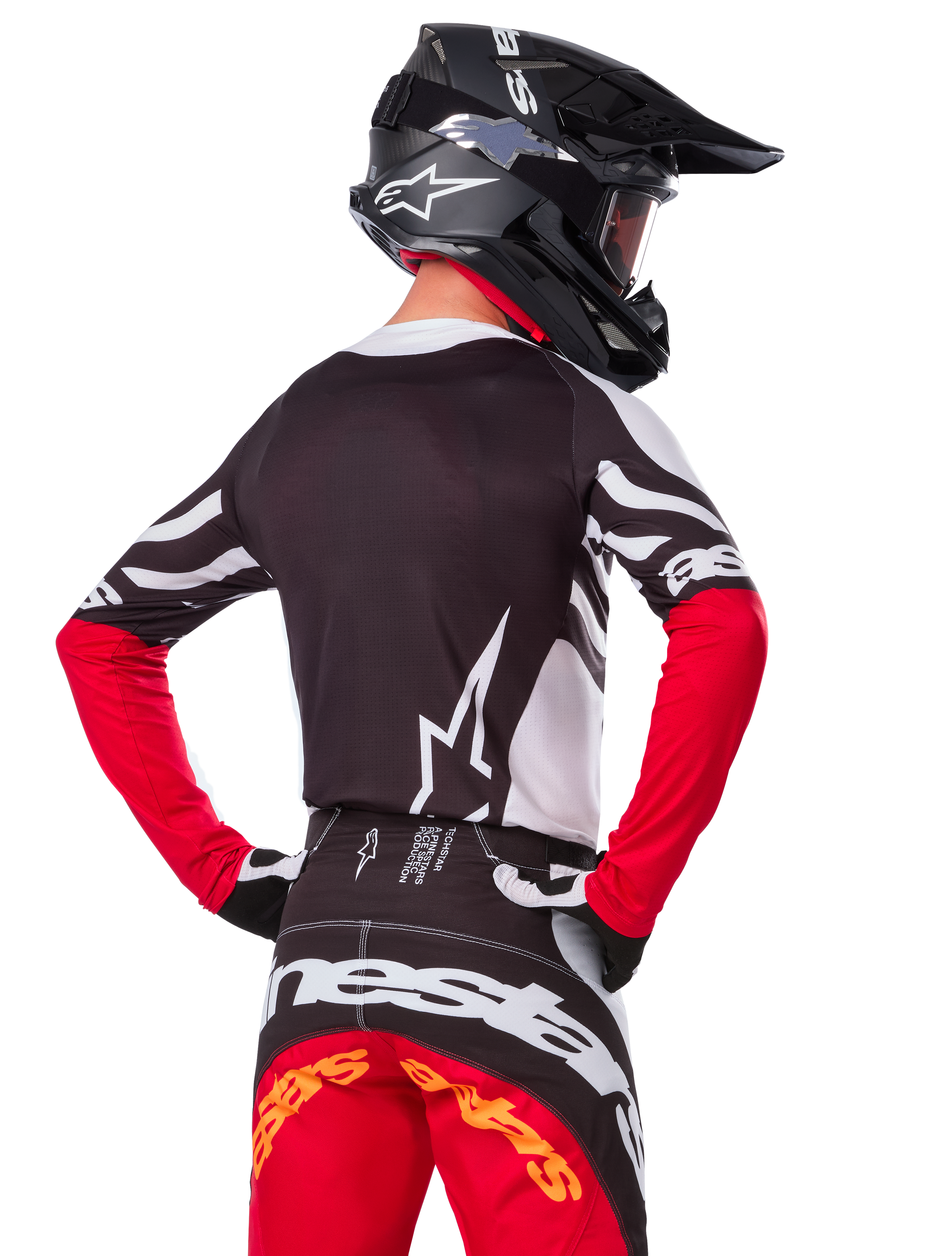 Motocrossrytter iført komplet racerudstyr, Alpinestars Limited Edition Techstar Deep jersey i sort, hvid og High Red, set bagfra, matchende Techstar Deep bukser, sort hjelm med goggles, sort-hvide handsker, professionelt off-road raceroutfit