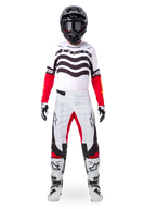 Motocross rider wearing the Alpinestars Limited Edition Techstar Deep Jersey in white, black, and red, featuring wavy chest graphics, paired with matching white and red pants, a black helmet, and white racing boots, full professional off-road gear setup.