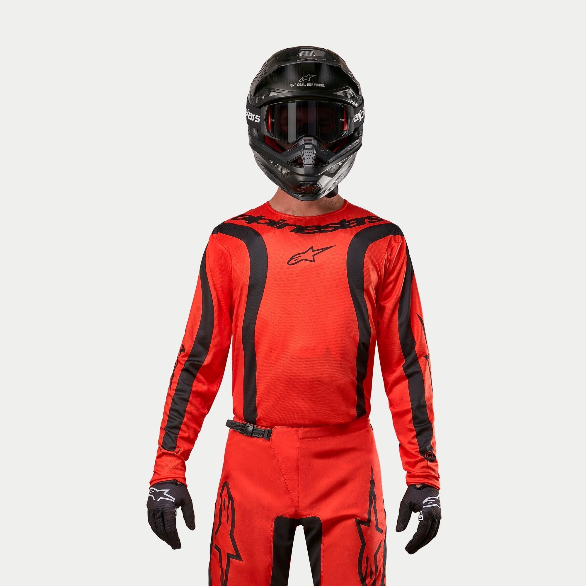 Motocrossrytter iført Alpinestars 2024 Fluid Lurv trøje, Hot Orange og sort, matchende motocrossbukser, sort hjelm med goggles og sorte handsker, koordineret udstyr til off-road racing