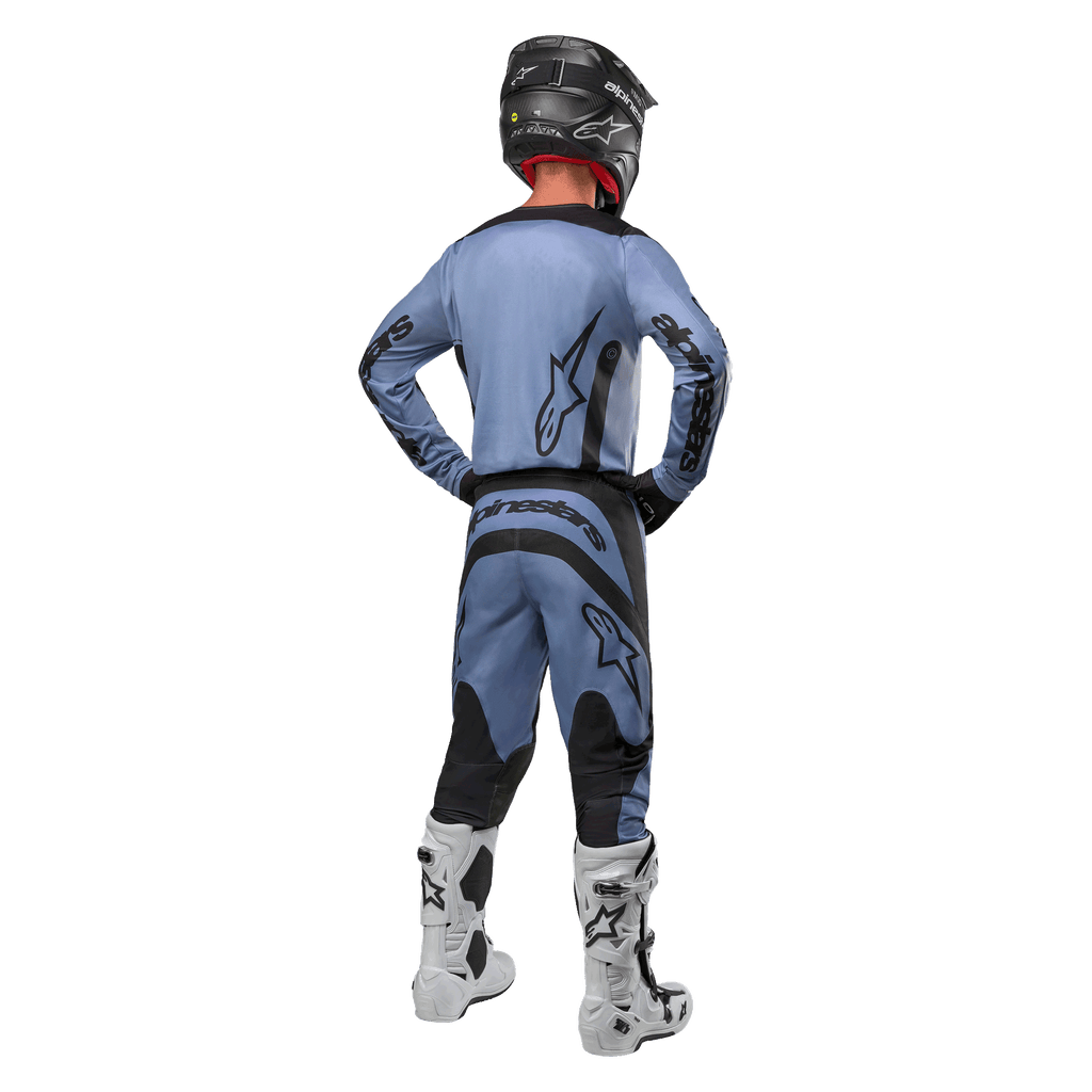 Motocross-rytter set bagfra iført Alpinestars 2024 Fluid Lurv-trøje og matchende bukser i lyseblå og sort, med sort branding på ryggen og ærmerne, kombineret med en sort hjelm og hvide støvler.