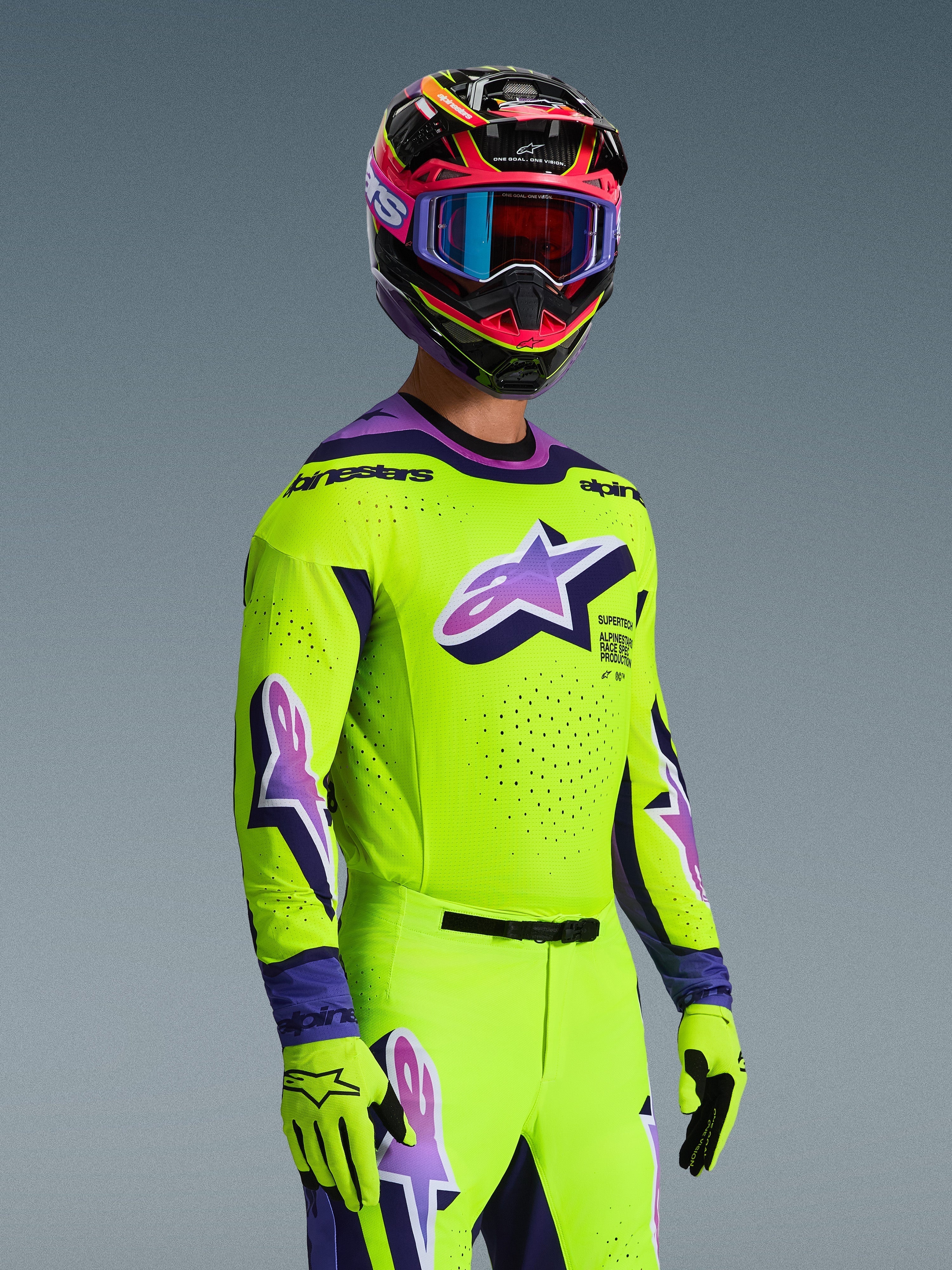Motocross-kører iført Alpinestars 2026 Supertech Vista Jersey, skriggul med lilla og sorte detaljer, matchende gule bukser og handsker, flerfarvet hjelm med lilla goggles, med laserskårne perforationer og et stort Astar-logo på brystet, koordineret racing-outfit på pro-niveau
