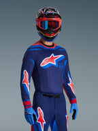 Motocross-kører iført 2026 Supertech Vista jersey i Dark Navy, Hot Coral og Cobalt, matchende bukser og handsker, flerfarvet hjelm med røde goggles, professionelt udstyrssæt til terrænkørsel