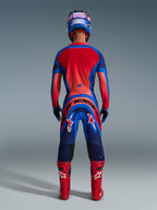 Alpinestars 2026 Supertech Vista trøje, motocross-kører set bagfra i Dark Navy, Hot Coral og Cobalt, matchende udstyrssæt med bukser, røde racestøvler og blå hjelm, professionelt terrænkørselsudstyr