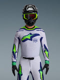 Alpinestars 2026 Supertech Vista trøje, motocross-jersey, lysegrå, neon-gul og blå, båret af en kører med matchende bukser og sort hjelm, med et stort brystlogo og laser-skårne perforeringer til ventilation, atletisk pasform på pro-niveau