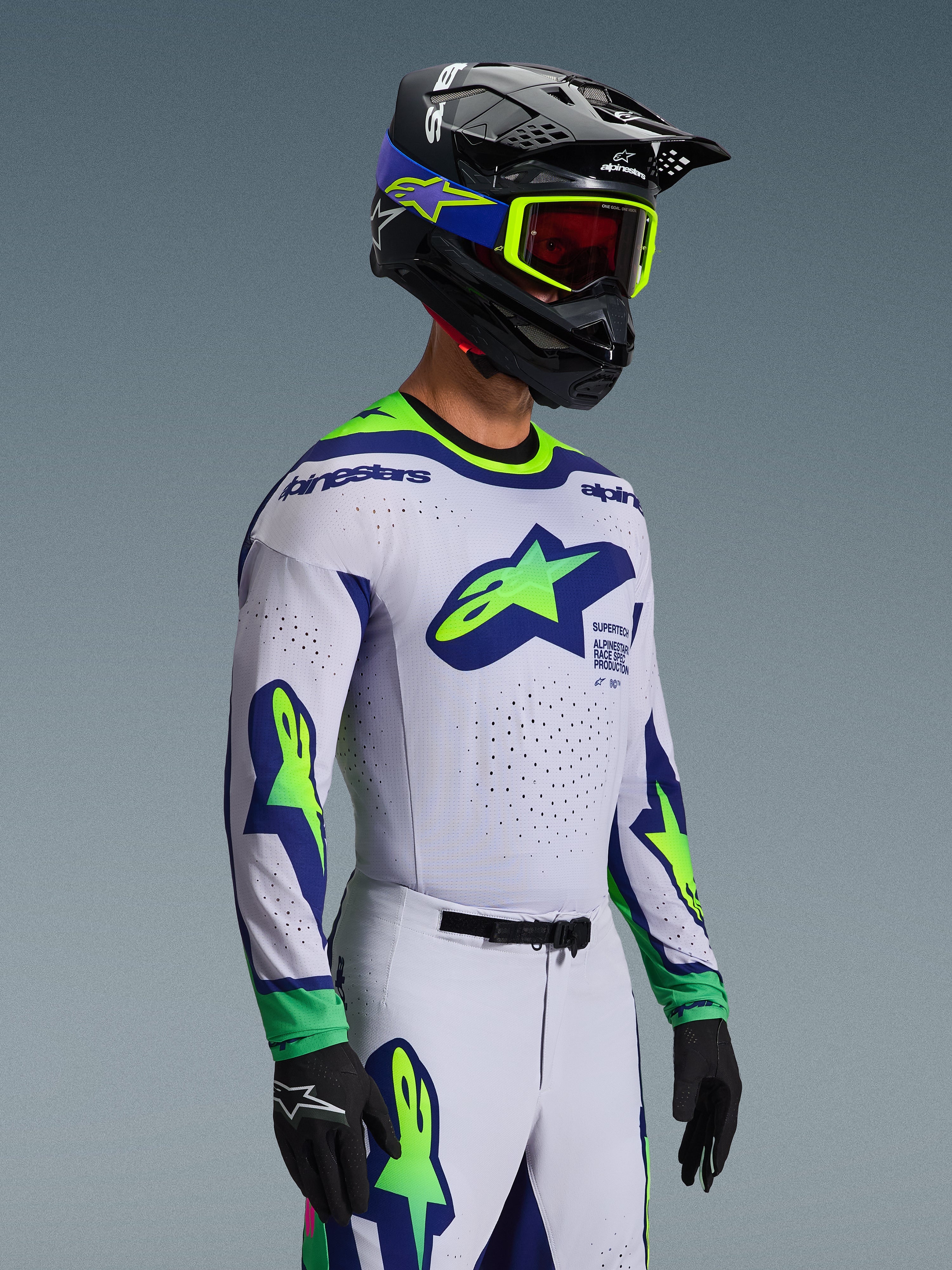 Motocross rider wearing the 2026 Supertech Vista Jersey in Light Gray with Yellow Fluo and Blue accents, featuring large star logos on chest and sleeves, matching pants and helmet with fluo goggles, black gloves, pro-level motocross gear