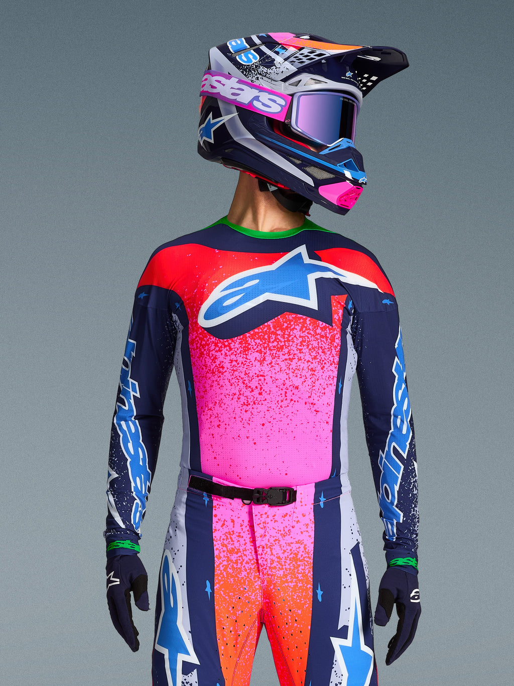 Alpinestars Limited Edition Supertech Records Jersey, motocross-kører iført pink og navy design med orange nistrede mønstre og lyseblåt stjernelogo, matchende hjelm og goggles, professionelt racerudstyr
