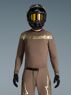 Alpinestars Begrænset udgave Supertech Air Gold trøje, motocrosstrøje, brun og guld, laserskåret ventilation, båret af en rytter med hjelm og goggles