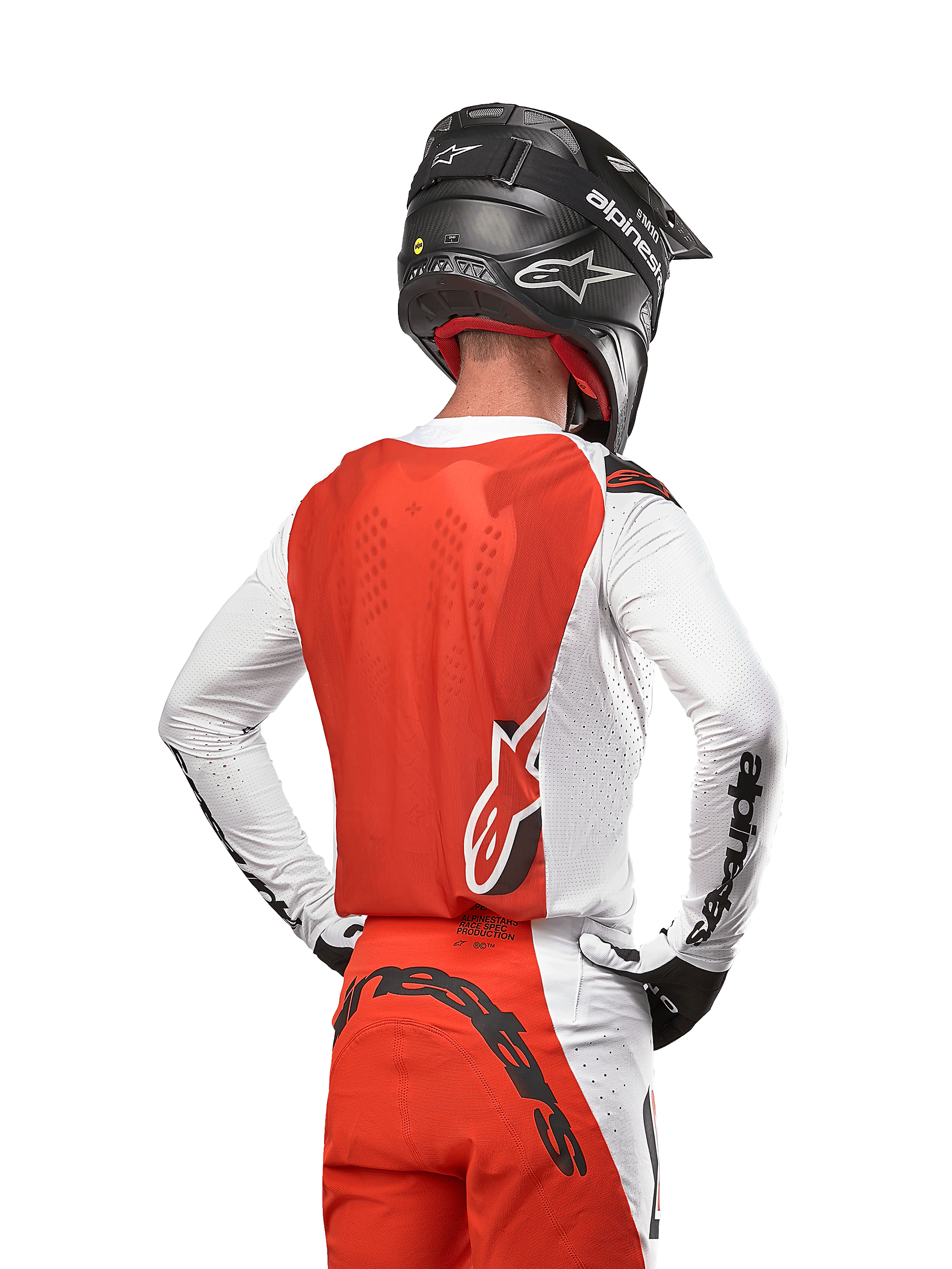 Motocross-rytter iført 2024 Supertech Ward Jersey i farven White Hot Orange, set bagfra, viser det orange rygpanel og de hvide ærmer med sort Alpinestars-branding, kombineret med matchende bukser og sort hjelm, professionelt udstyr til off-road racing
