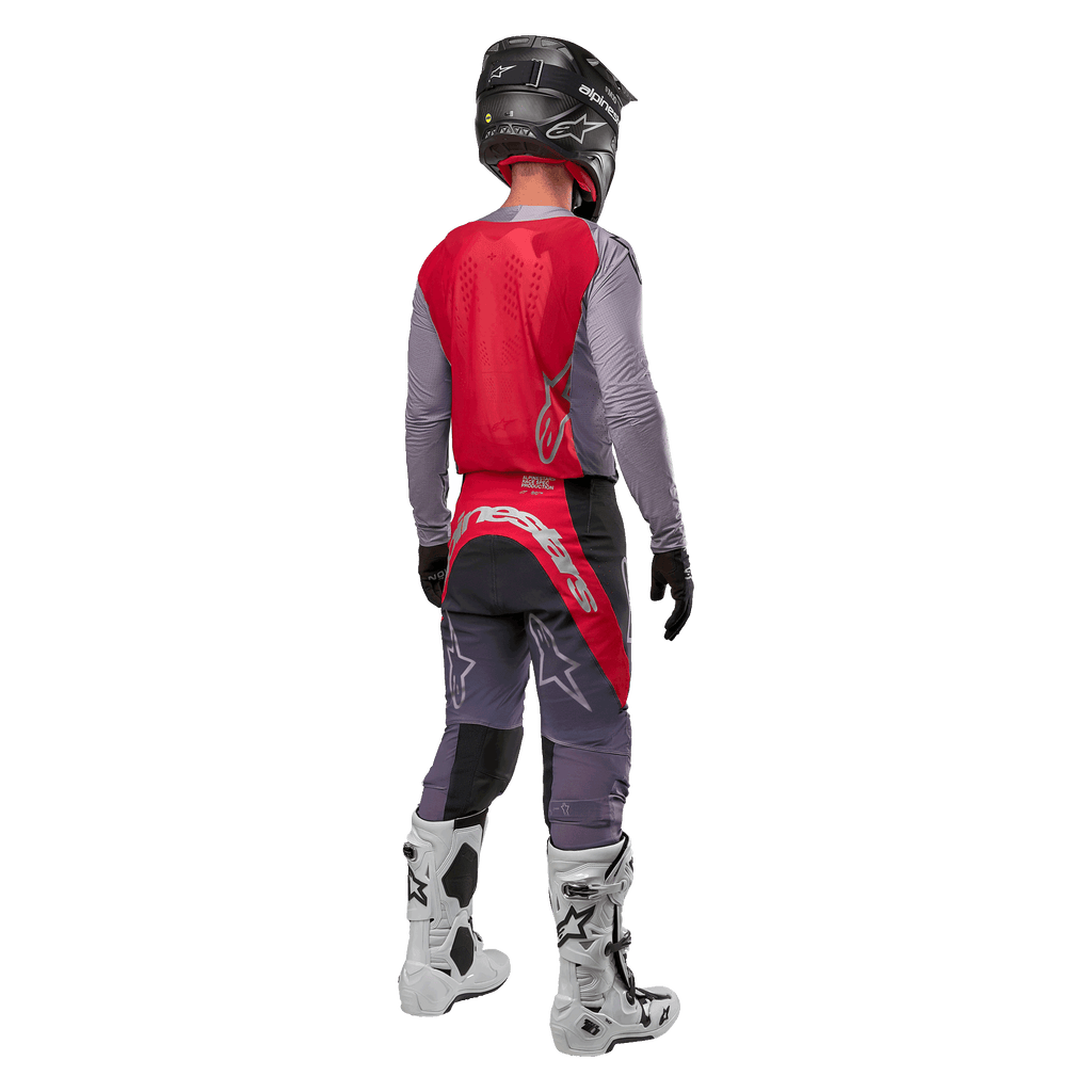 Alpinestars 2024 Supertech Dade trøje, motocross-trøje, Iron Red Berry og grå, set bagfra på en kører, med et rødt rygpanel med gråt logo og grå ærmer, båret med matchende grå og røde racerbukser, hvide støvler og en sort hjelm, professionelt terrænkørselsudstyr