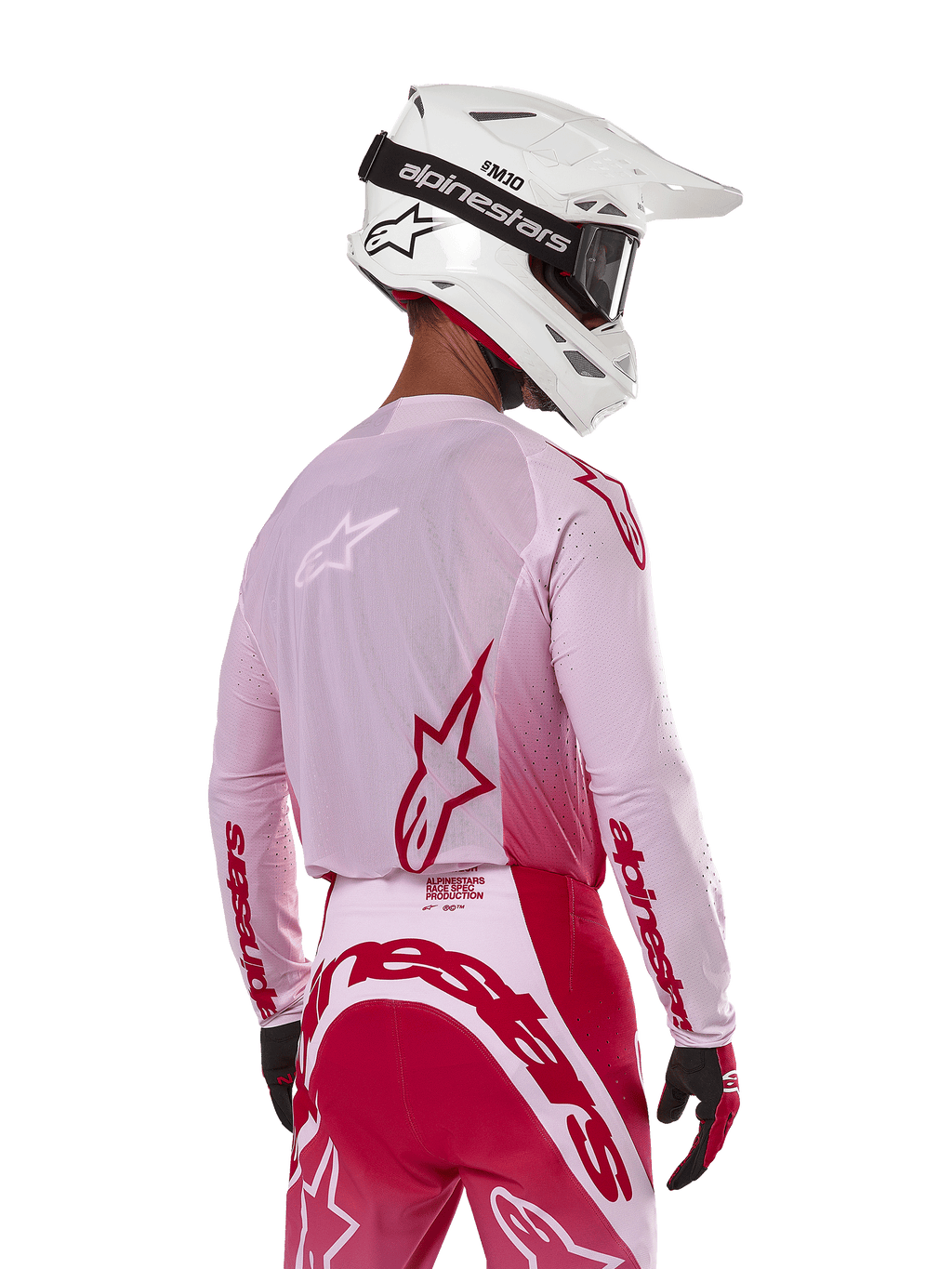 Motocrossrytter set bagfra iført Alpinestars 2024 Supertech Dade Jersey i Red Berry Lilac, med åndbare mesh-paneler og røde Alpinestars-logoer, kombineret med matchende røde og lilla bukser og en hvid Alpinestars-hjelm med goggles, professionelt off-road racerudstyr
