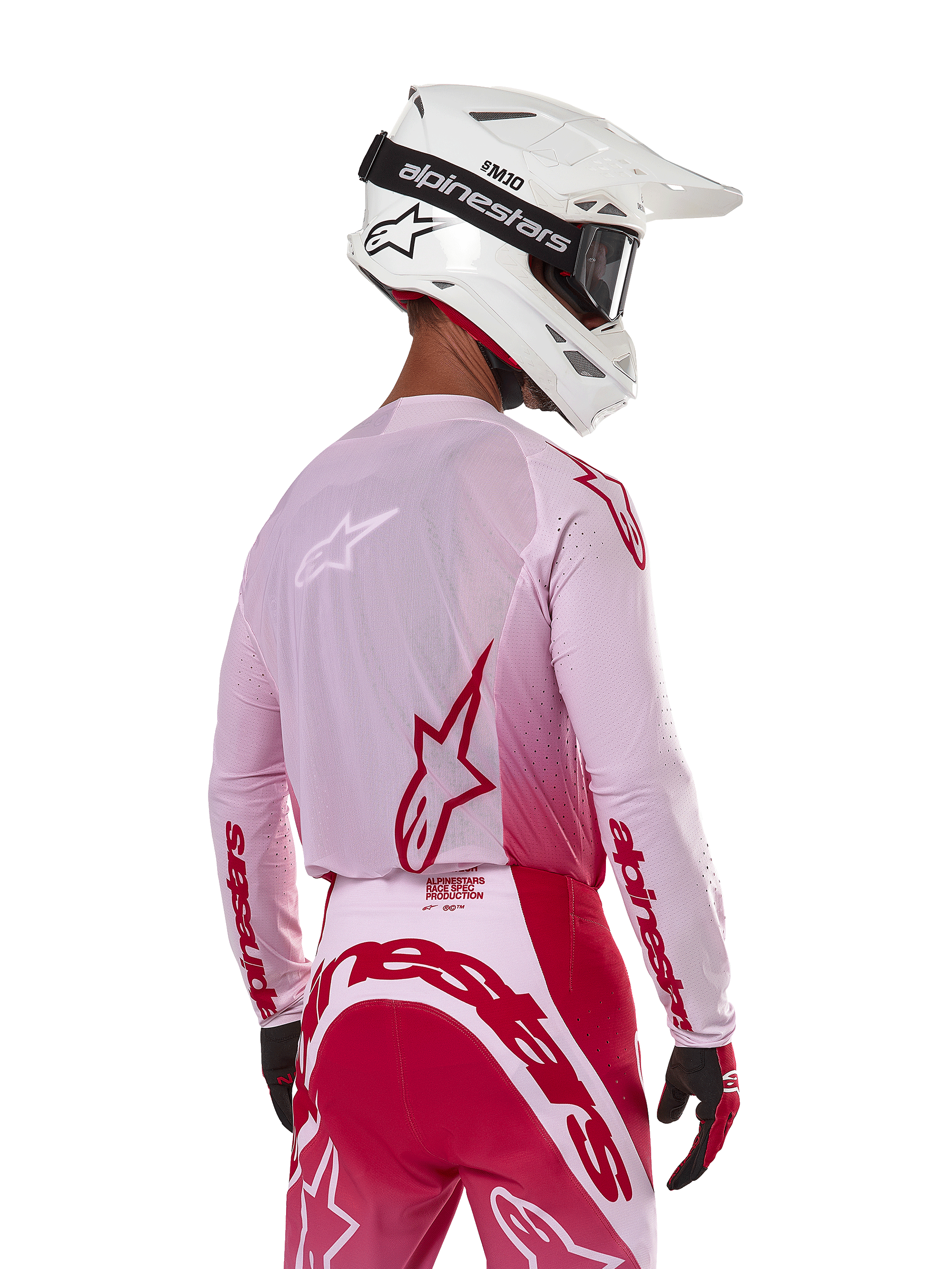 Motocrossrytter set bagfra iført Alpinestars 2024 Supertech Dade Jersey i Red Berry Lilac, med åndbare mesh-paneler og røde Alpinestars-logoer, kombineret med matchende røde og lilla bukser og en hvid Alpinestars-hjelm med goggles, professionelt off-road racerudstyr