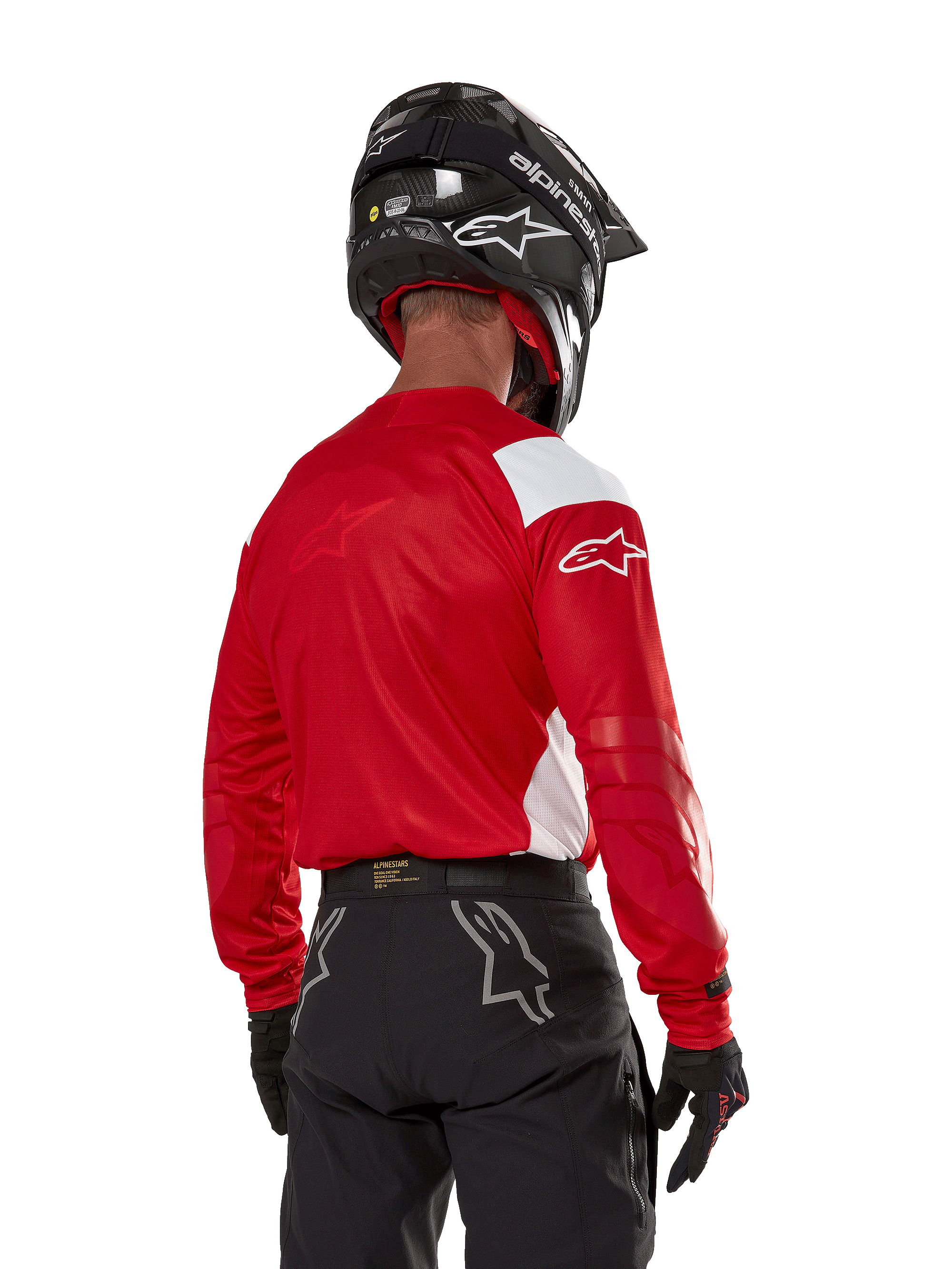 Motocross-kører set bagfra iført Alpinestars Techdura Jersey i Bright Red med hvide paneler, kombineret med sorte off-road bukser, sort hjelm og sorte handsker, koordineret udstyr til enduro- og motocross-kørsel.