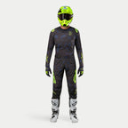 Alpinestars motocross-rytter iført komplet racerudstyr, 2024 Techstar Rantera trøje i Black Navy og Yellow Fluo, matchende bukser med abstrakt print, klar neongul hjelm, hvide og sorte støvler, koordineret outfit til off-road kørsel