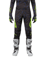 Alpinestars 2024 Techstar Rantera bukser, motocross-bukser, sort, navy og neon-gul, båret med matchende langærmet trøje, handsker og hvide motocross-støvler, med markante neon-gule detaljer og et abstrakt mørkt mønster.