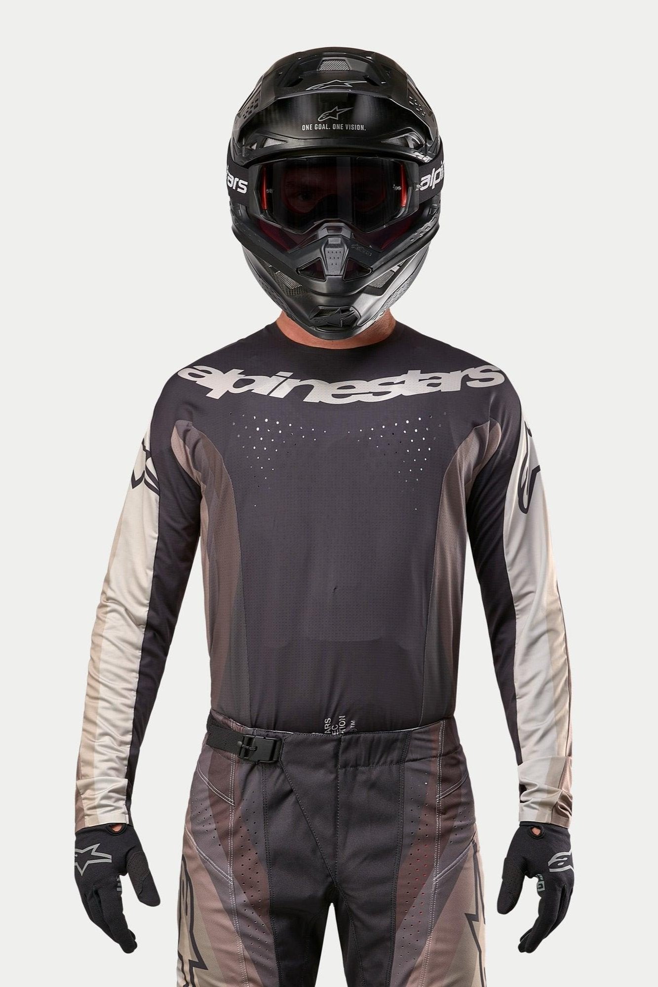 Alpinestars 2024 Techstar Pneuma trøje, motocross trøje, Dark Sand og Iron Dust grå, kombineret med matchende motocrossbukser og en sort hjelm, markant Alpinestars-logo på brystet, laserskårne ventilationsperforeringer, professionelt racingudstyr til off-road.