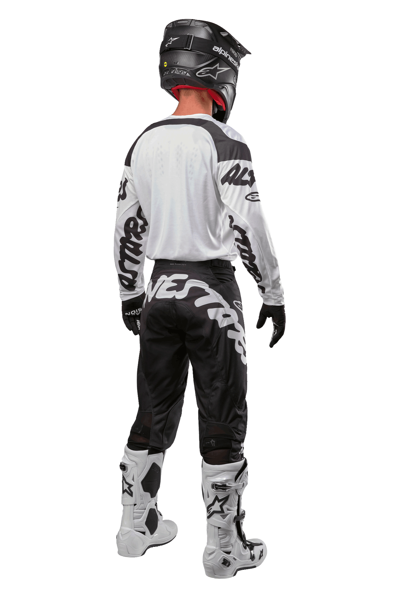 Alpinestars 2024 Racer Hana trøje, motocross-rytter set bagfra, hvid og sort, hvid trøje med sort grafisk branding på ærmerne, kombineret med sorte bukser med hvid Alpinestars-tekst på bagdelen, sort hjelm og hvide og sorte støvler, matchende off-road racing-udstyr